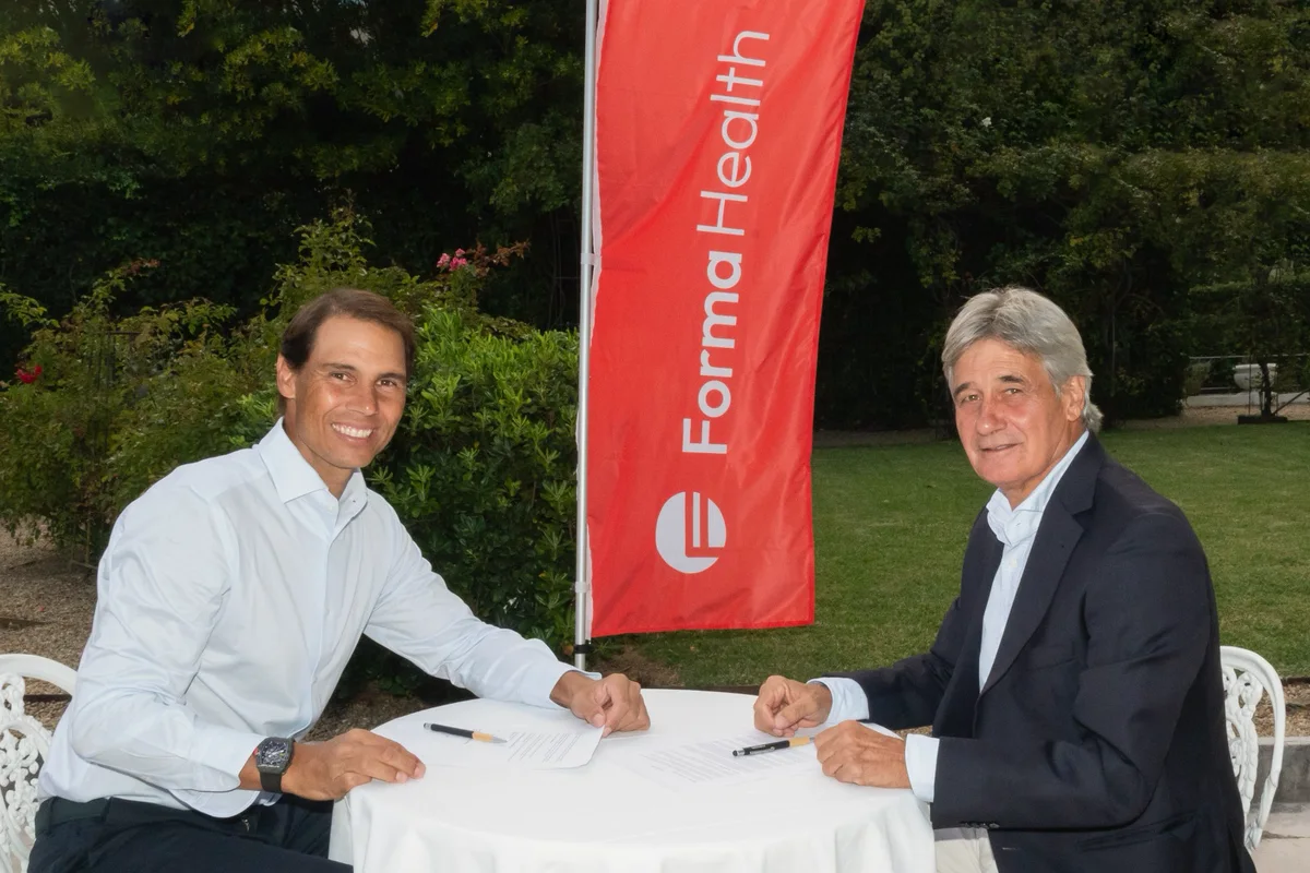 Rafa Nadal and Dr. Ángel Ruiz-Cotorro sign the agreement next to the Forma Health banner